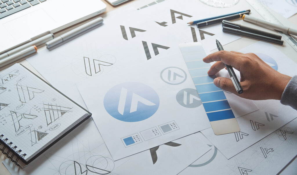 Designer selecting brand colors and sketching logo concepts during visual identity development as part of branding services.