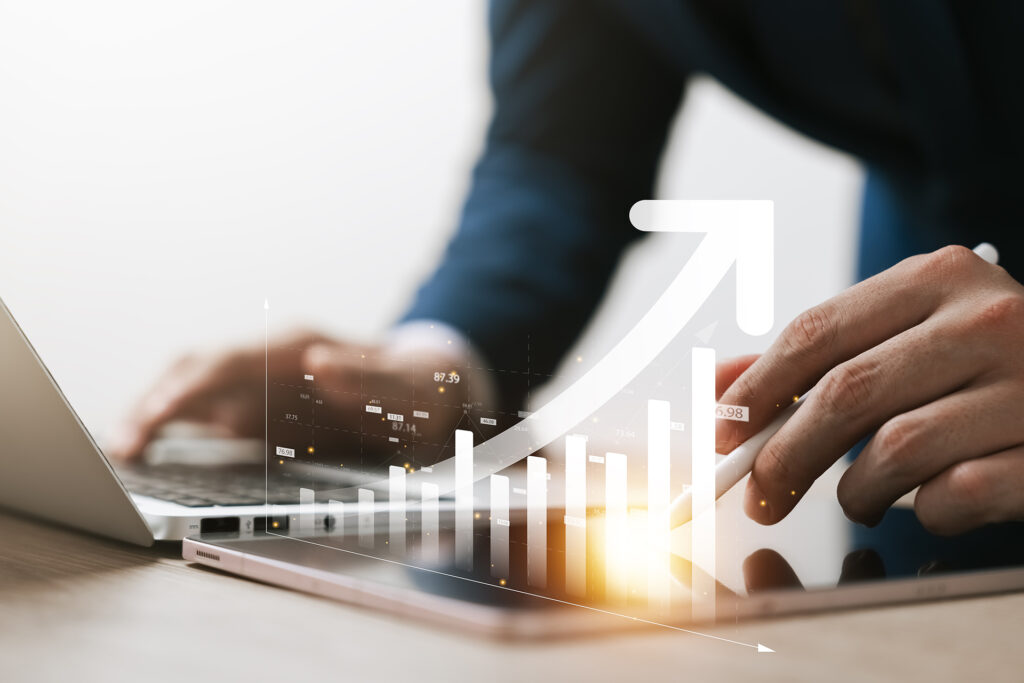 Business professional analyzing data on a tablet with rising bar chart overlay.