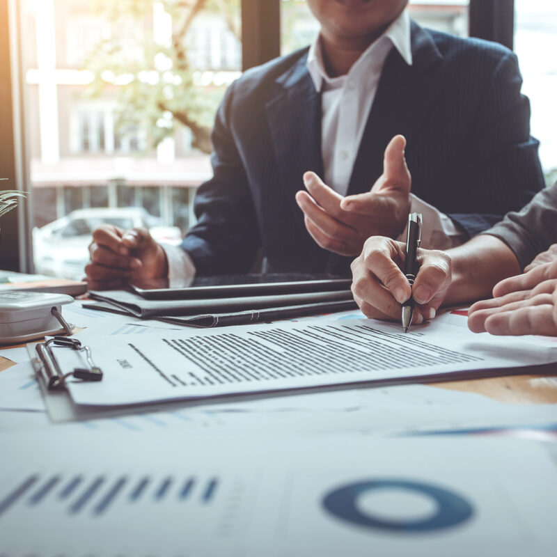 Two business professionals reviewing marketing strategy and signing documents at a meeting table